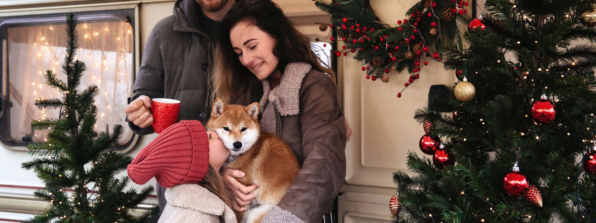 Foreldrepar med hund foran en jule-dekorert bobil