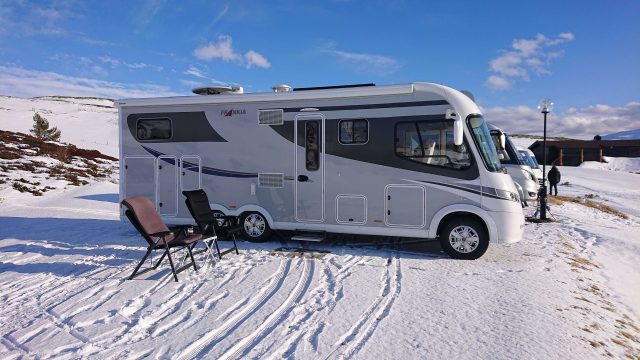 Bobil i sol på snødekt campingplass